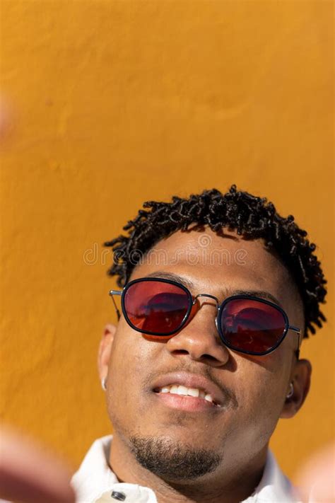 vertical portrait close up black latino man with sunglasses smiling taking a selfie with his