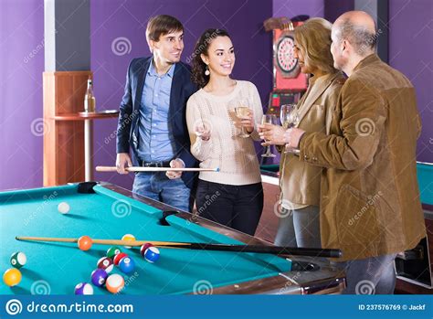 Mature And Young Couples Hanging Out In Billiard Club Together Stock