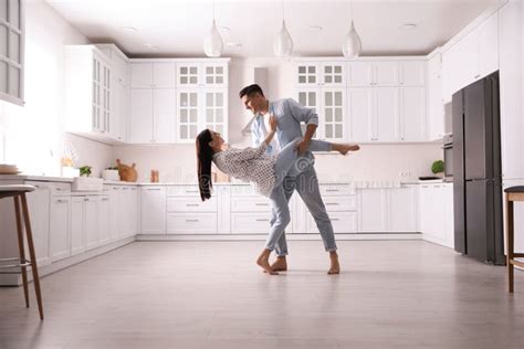 Happy Couple Dancing Barefoot In Kitchen Floor Heating System Stock