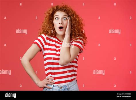 shocked amused emotive redhead ginger girl curly haircut popping eyes stare camera fascinated