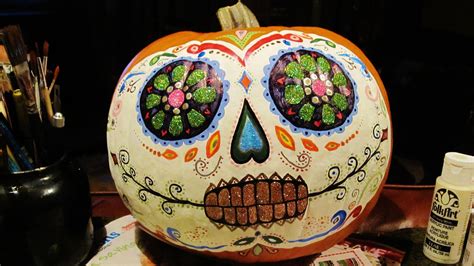 A Pumpkin Decorated With Flowers And Leaves On Top Of A Table Next To