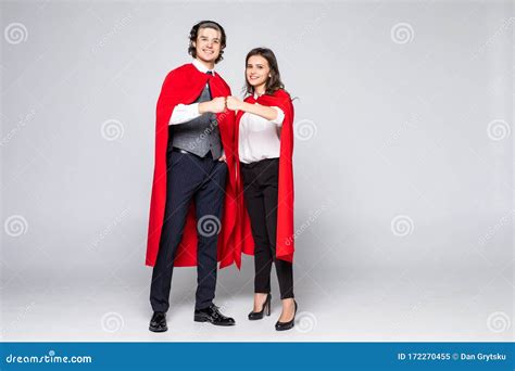 Young Couple Of Superheroes In Costumes Standing With Hands To Hands