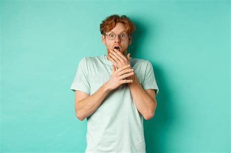 Shocked Redhead Man In Glasses Gasping Startled Covering Mouth And Staring At Camera Scared