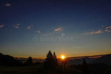Shining Sun At A Warm Sunrise With Colorful Sky And Dark Landscape