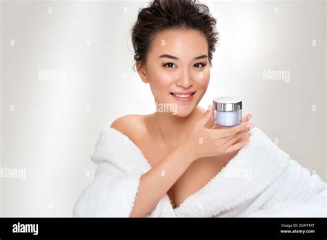 woman holds jar with cosmetic cream photo of asian woman after shower on white background