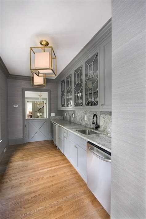 A white pocket door opens to a well appointed gray kitchen pantry boasting gray cabinets donning brass hardware. Gray Butlers Pantry - Transitional - kitchen - Amanda Orr ...