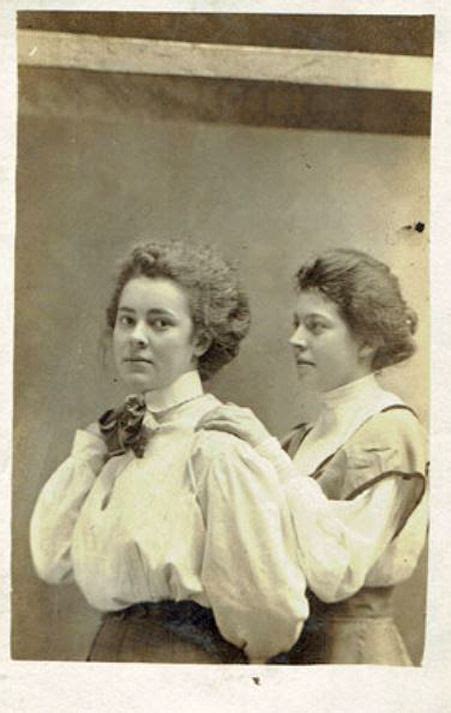 An Old Photo Of Two Women Standing Next To Each Other In Front Of A Mirror