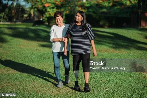 Asian Indian Handicapped With Prosthetic Leg And Active Senior Chinese Smiling Woman Holdings