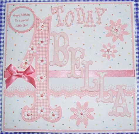Embossed baby feet on a matted square with pearls at the four corners. Poppyscabin: Baby Girl's First Birthday card