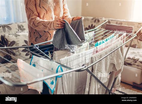 Woman Folding Gathering Clean Clothes From Dryer After Washing At Home