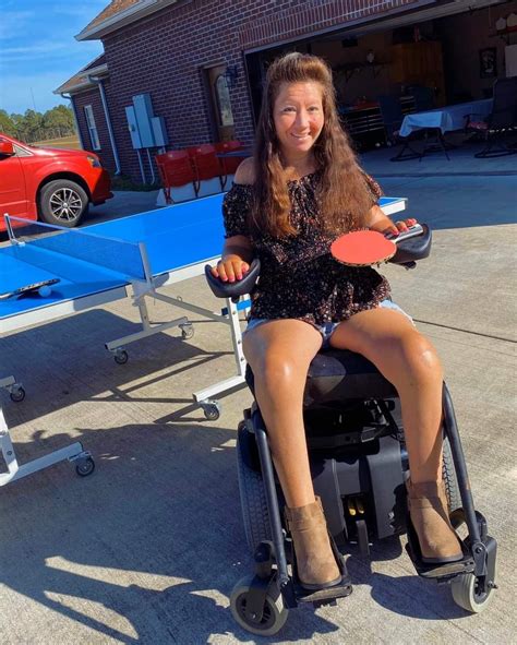 A Woman Sitting In A Wheel Chair Holding A Ping Pong Paddle