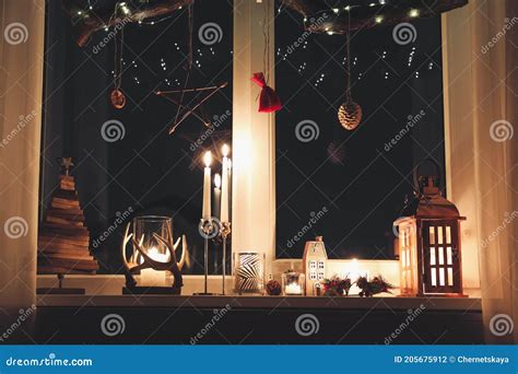 Burning Candles And Christmas Decor On Window Sill At Night Stock Photo