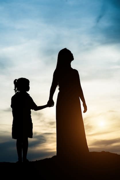 Silhouette Of Mother With Her Daughter Standing And Sunset Photo Free