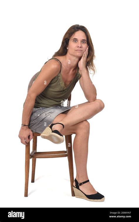 vue avant d une femme en jupe assise sur une chaise sur fond blanc regardant la caméra et les