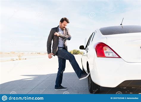 Annoyed Latin Man Kicking The Car S Flat Tire Stock Photo Image Of