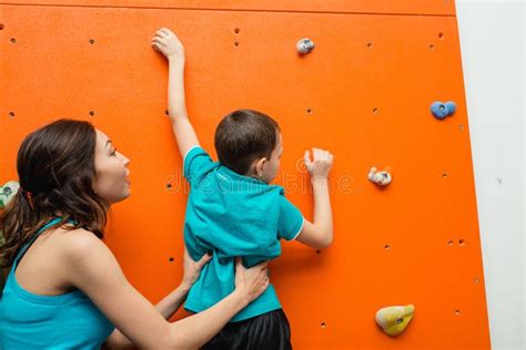 Helping Her Boy To Climb On A Wall In Bouldering Gym On Playground