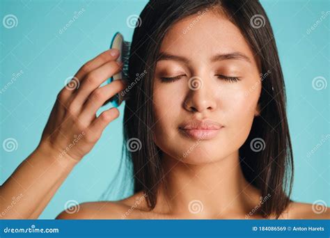 Beautiful Asian Brunette Girl Dreamily Combing Hair Over Colorful Background Isolated Stock