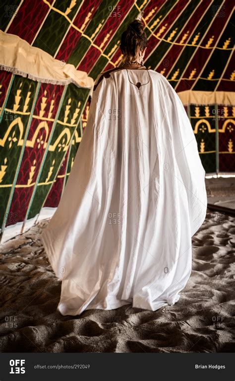Are there any photos of the lower back? Back view of woman in a white robe inside a tent on sand stock photo - OFFSET