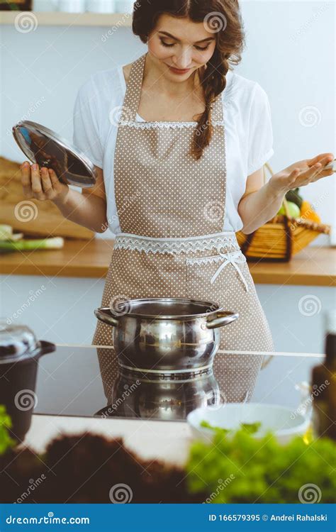 Young Brunette Woman Cooking Soup In Kitchen Housewife Holding Wooden Spoon In Her Hand Stock