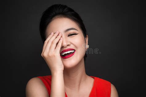 Smiling Shy Woman Closed Her Face With A Hand Over Black Background