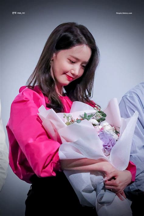 A Woman Holding A Bouquet Of Flowers In Her Hands