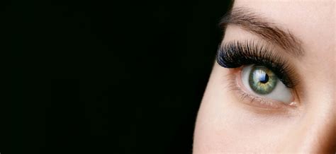close up vista verde olhos femininos com cílios longos em fundo escuro foto premium