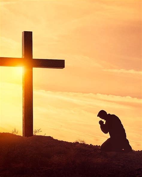 A Man Kneeling Down In Front Of A Cross