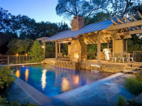 An Outdoor Kitchen Fireplace And Dining Area Are Connected To A Pool