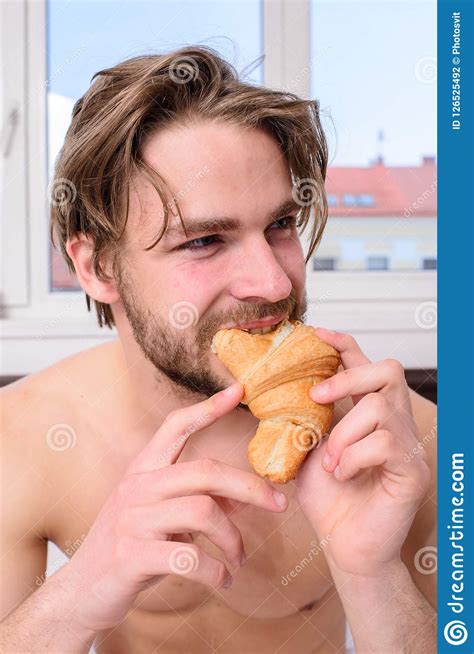 Handsome Man Eating Cereal At Breakfast Table With Open Blue Shirt Revealing Defined Chest And