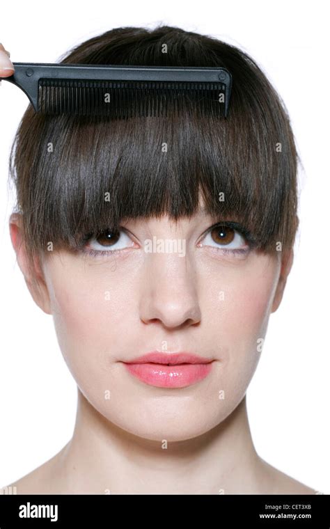 Female With Fringed Brunette Hair Tied At The Back Combing Fringe With