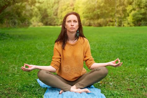 A Lovely Woman Meditates Sitting On The Green Grass In The Park Stock Photo At Vecteezy
