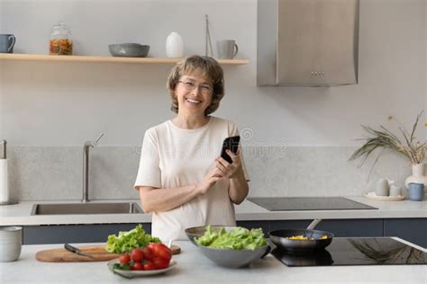 Happy Mature Homeowner Woman Using Mobile Phone In Kitchen Stock Image Image Of Culinary