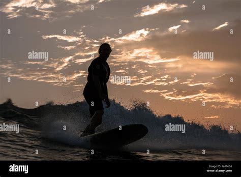 Silueta De Un Surfista En Su Tabla De Surf Montando Una Onda Al