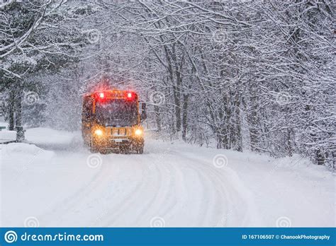School Bus Travelling On A Snow Covered Rural Road With Stop Lights