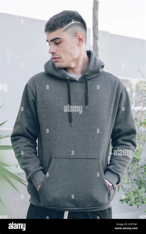 Portrait Of Young Man In Gray Hoodie Hiding Hands In Pockets Looking