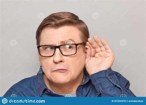 Portrait Of Curious Man Placing Hand Near Ear And Eavesdropping Stock