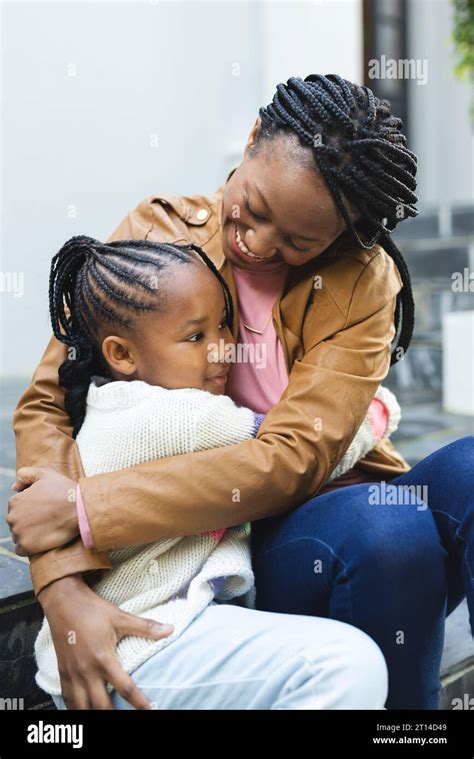 Happy African American Mother And Daughter Embracing On Steps In Front