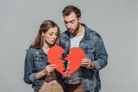 Upset Young Couple Holding Parts Of Broken Heart Symbol Stock Photo