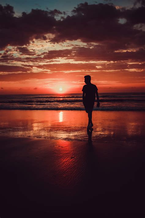 Silhouette Of Man Standing On Beach During Sunset · Free Stock Photo