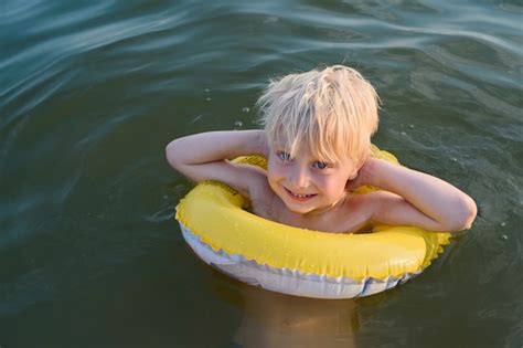 Premium Photo Blond Boy Swims With Yellow Floaties Vacation Sea With