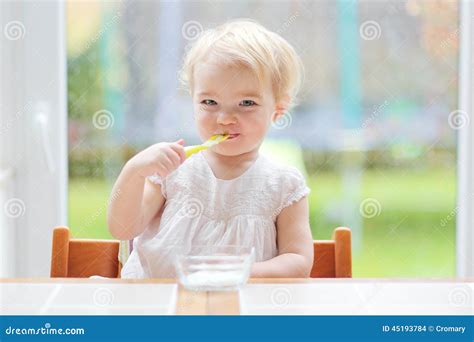 Cute Baby Girl Eating Yogurt From Spoon Stock Photo Image Of Chair