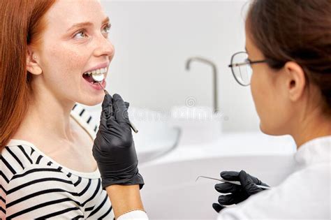 una mujer caliente atractiva del dentista del pelirrojo tomando cuidado de su paciente foto de