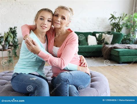 Beautiful Senior Mom And Her Adult Daughter Are Hugging Looking At Camera And Smiling Stock