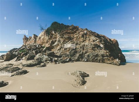 Eroded Rock Formation On Sandy Ocean Beach At High Noon Casting Long