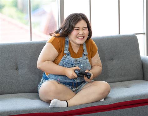 Portrait Of Chubby Asian Woman Sitting And Holding A Joystick Looking