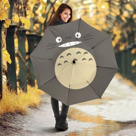 A Woman Holding An Umbrella With A Totoro Face On It
