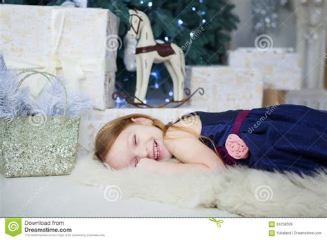 Kleines Mädchen In Einem Eleganten Kleid Liegt Und Lacht über Den Weihnachtsbaum Stockbild