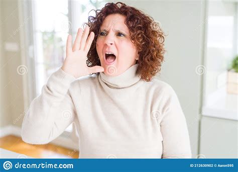 beautiful senior woman wearing turtleneck sweater shouting and screaming loud to side with hand