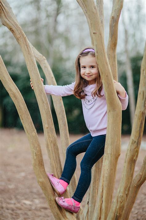 Cute Young Girl Climbing A Tree Outside Del Colaborador De Stocksy