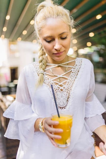 Free Photo Blonde Young Woman Holding Glass Of Mango Juice